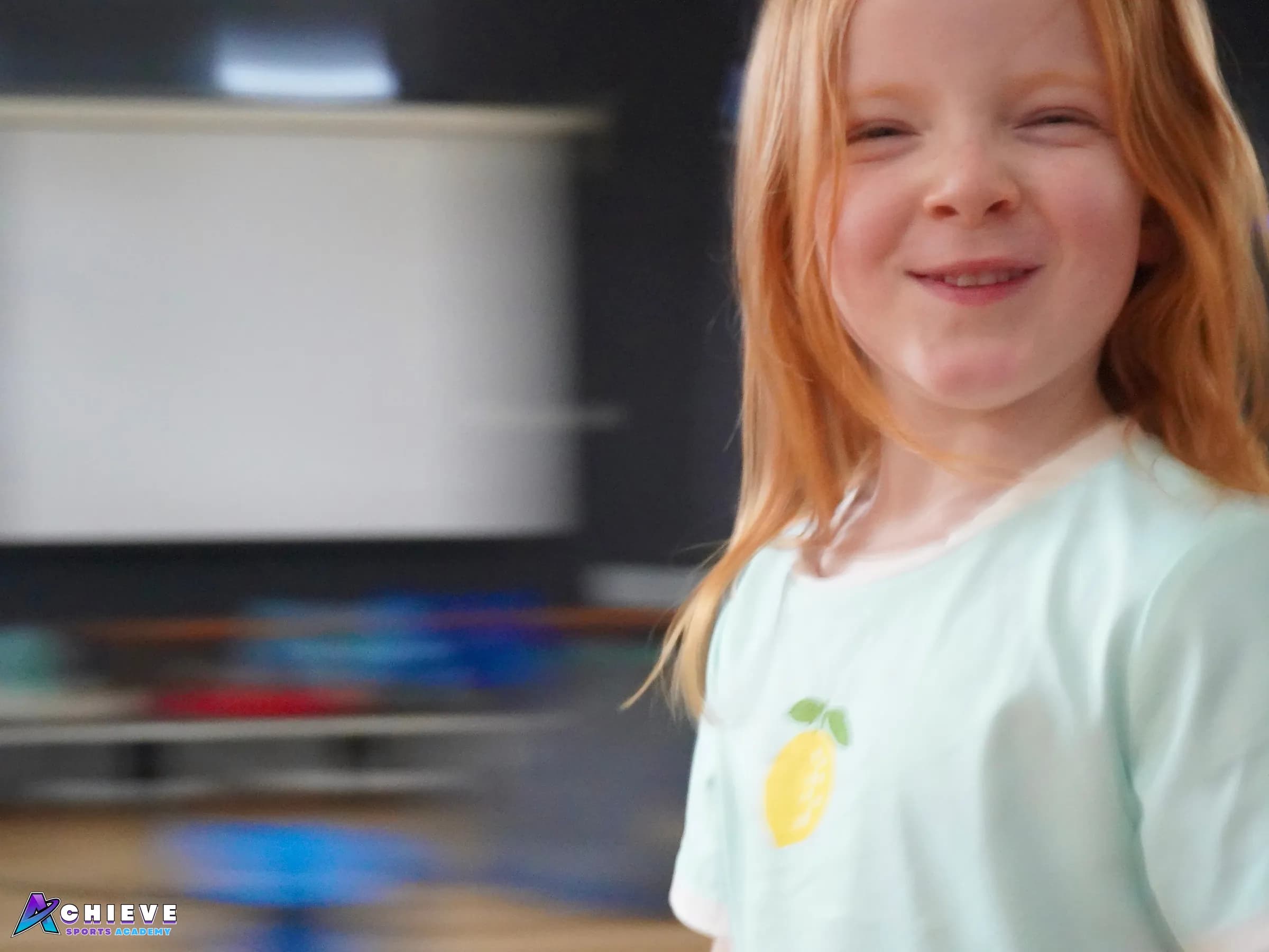 Smiling child enjoying a Play Learn Achieve session in the school hall