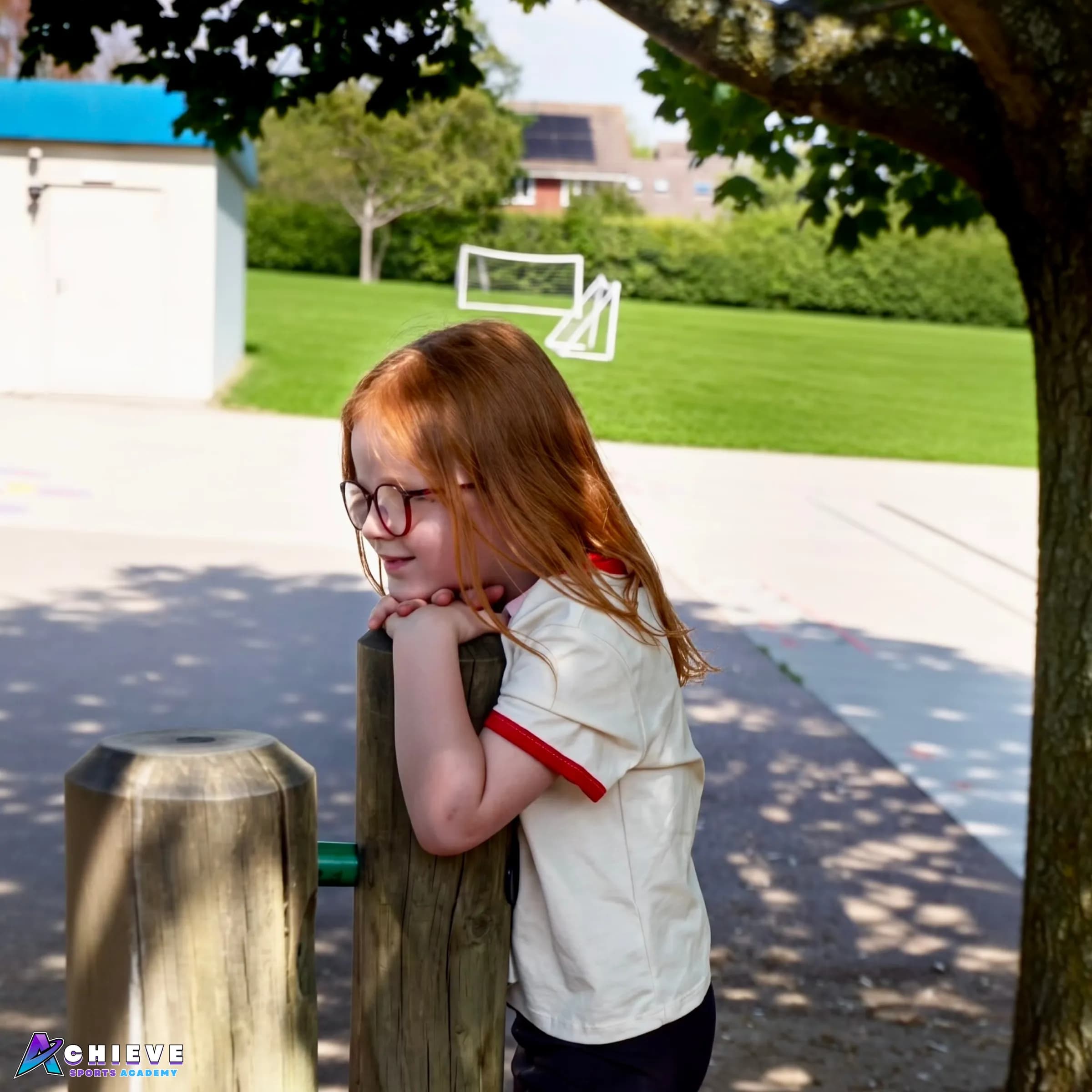 Child enjoying an outdoor session beside the school field with football goals behind