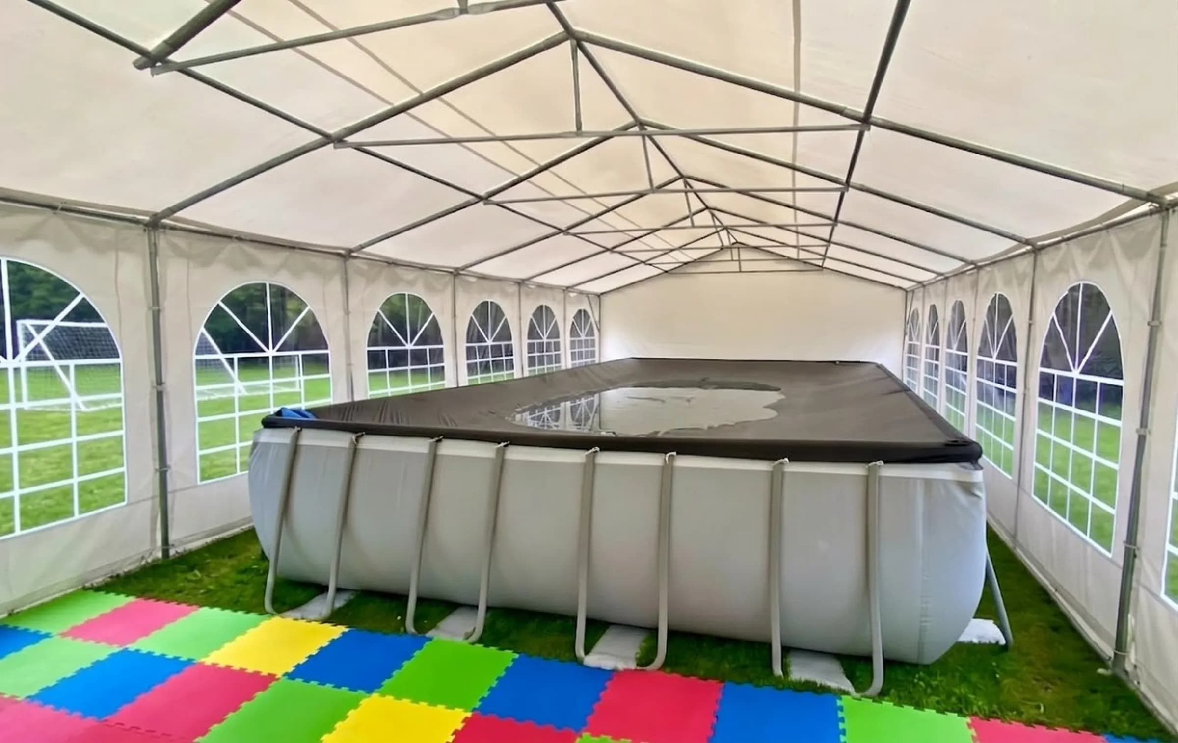 Illustrative temporary pool standing on grass with foam mats used as flooring