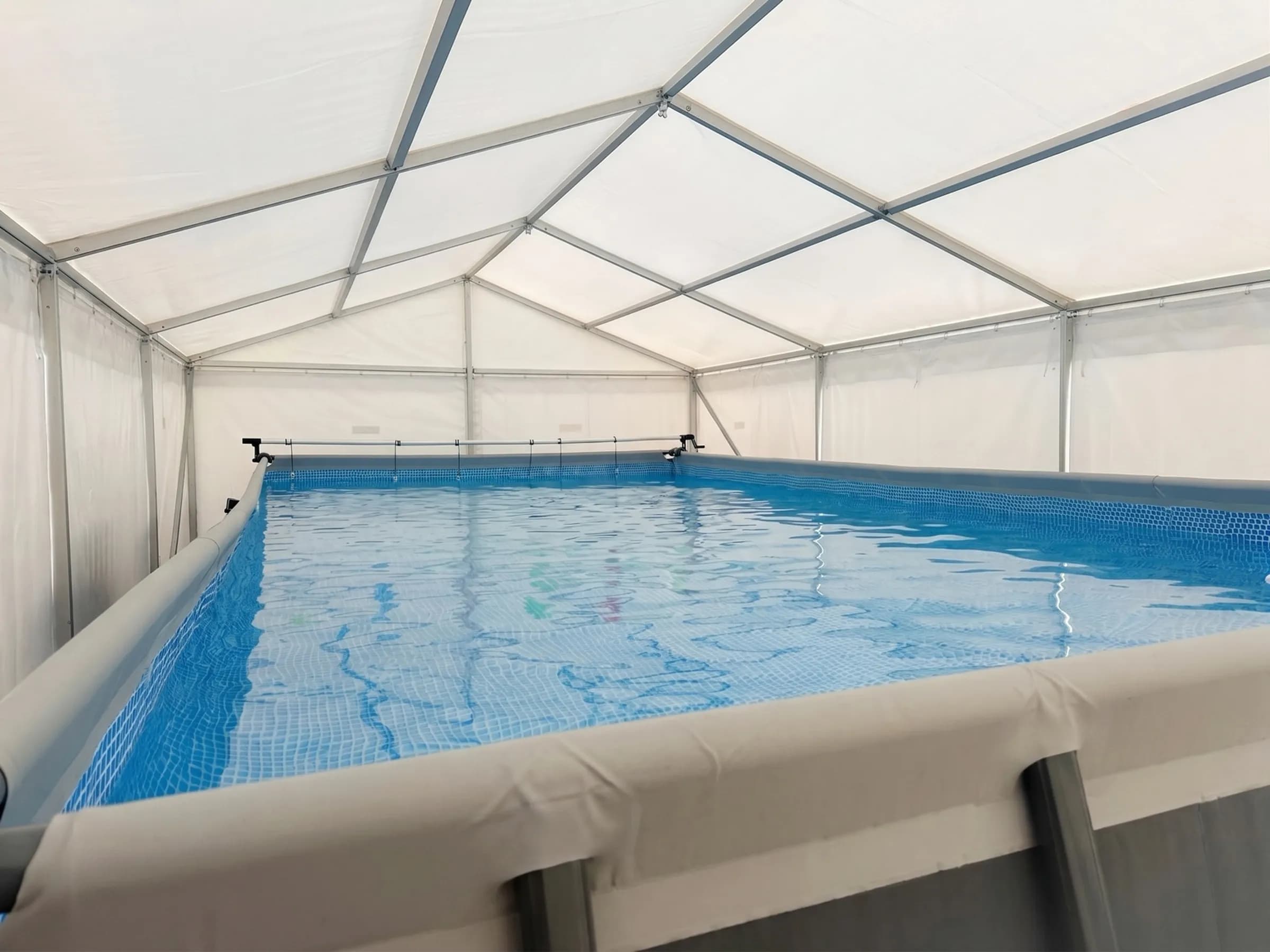 Temporary swimming pool positioned close to the surrounding vinyl marquee with restricted perimeter space